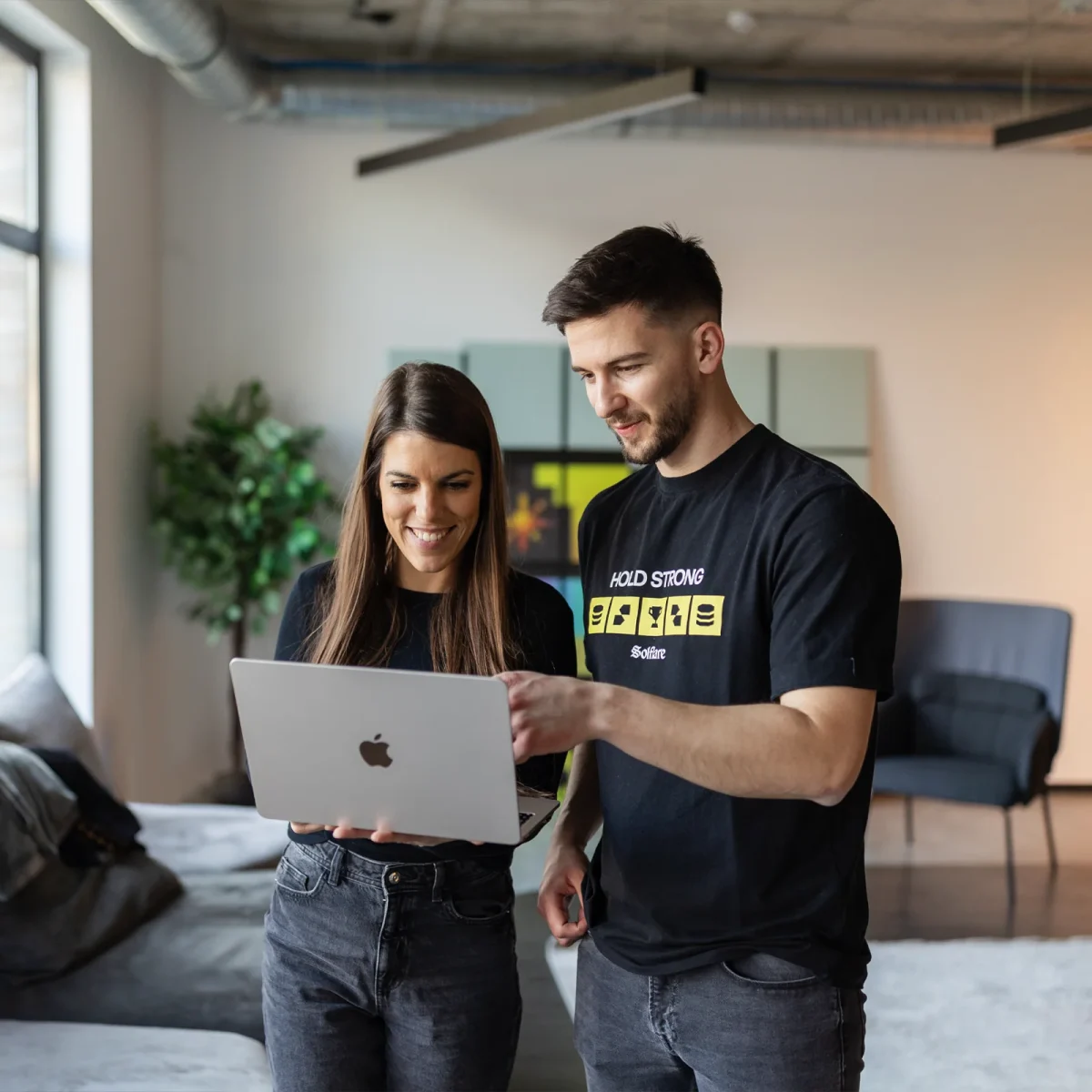 two colleagues standing and checking laptop